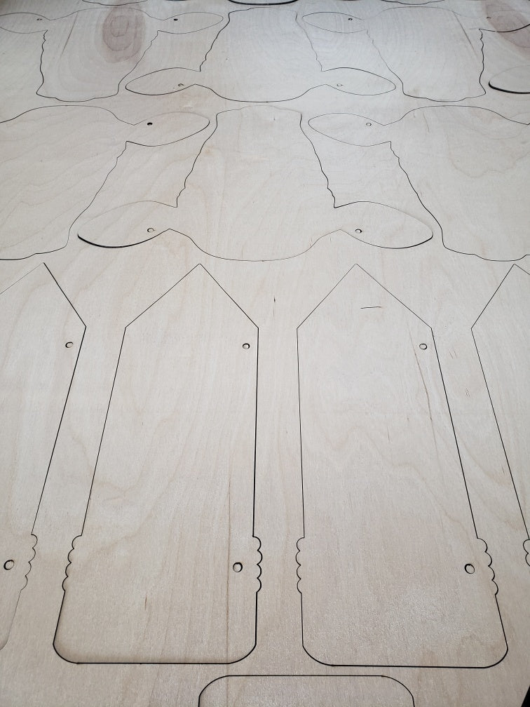 Unfinished laser-cut wood cutouts and door hanger blanks in round, pencil, cow head, cow tag, pumpkin, and ghost shapes